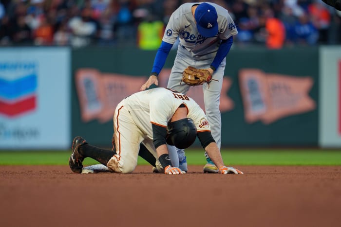 SF Giants first baseman Brandon Belt stays on the ground after an ugly slide into second base in front of Dodgers infielder Trea Turner. (2022)